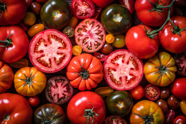 Several different varieties and colored tomatoes, some are whole and some are cut in half.